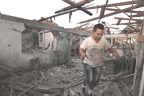 A resident of Netivot walking inside the house that was hit early Sunday morning by a long-range Grad rocket from Gaza.
