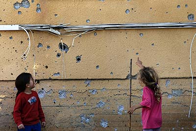 Young Kibbutz girls Kibbutz examine the shards on the wall by a qassam rocket.