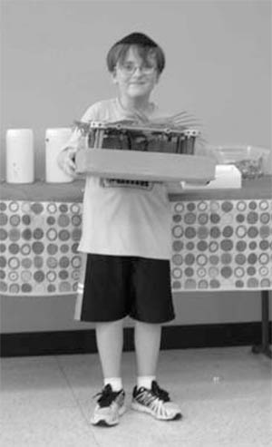 Contest winner Cole Benveniste-Plitt holds winning model sukkah.