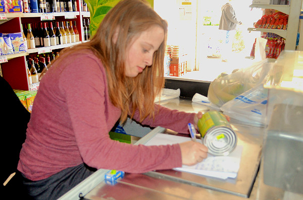 Yael Meir, cashier at SuperDeal, writing out customers' orders because the electricity was out. Feb. 6, 2015.