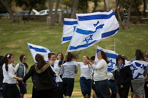 Girls dance with the national flag to celebrate Yom Ha'Atzmaut.